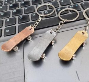 سلسلة مفاتيح لوح تزلج مصغرة بلون ذهبي وردي/نحاسي