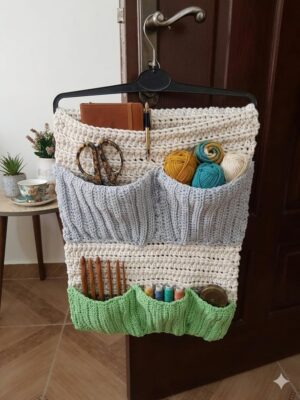 منظم حائط معلق للكروشيه مصنوع يدويًا - حامل متعدد الجيوب للخيوط والإكسسوارات - وحدة تخزين ديكورية من 3 طبقات لغرف الحرف اليدوية - أزرق، أخضر، وكريمي - 60 × 40 سم